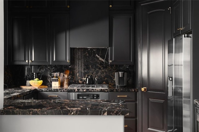 kitchen featuring dark stone countertops, tasteful backsplash, dark cabinets, and appliances with stainless steel finishes