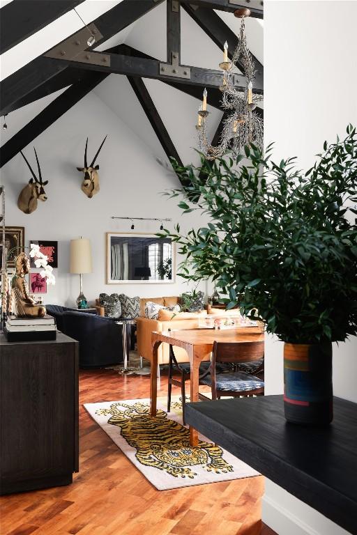 dining space featuring beam ceiling, high vaulted ceiling, and wood finished floors