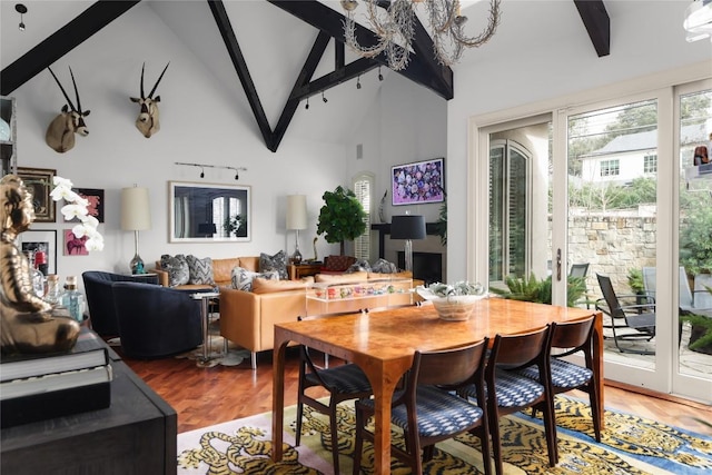 dining area with beamed ceiling, high vaulted ceiling, and wood finished floors