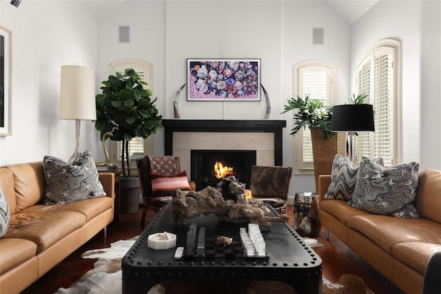 living room with visible vents, a warm lit fireplace, wood finished floors, and a healthy amount of sunlight