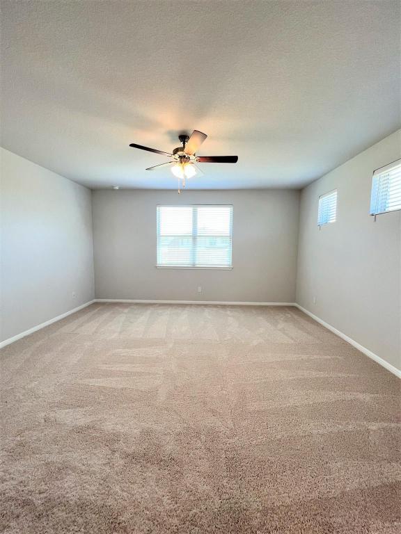 empty room featuring a healthy amount of sunlight, baseboards, and a textured ceiling