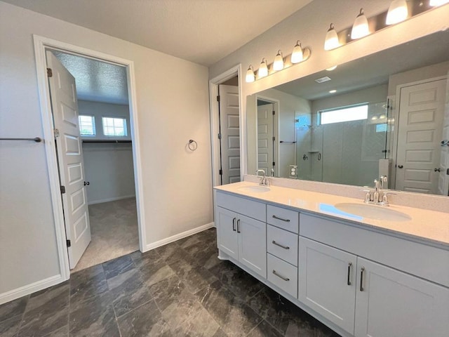 bathroom featuring a stall shower, a sink, baseboards, and double vanity