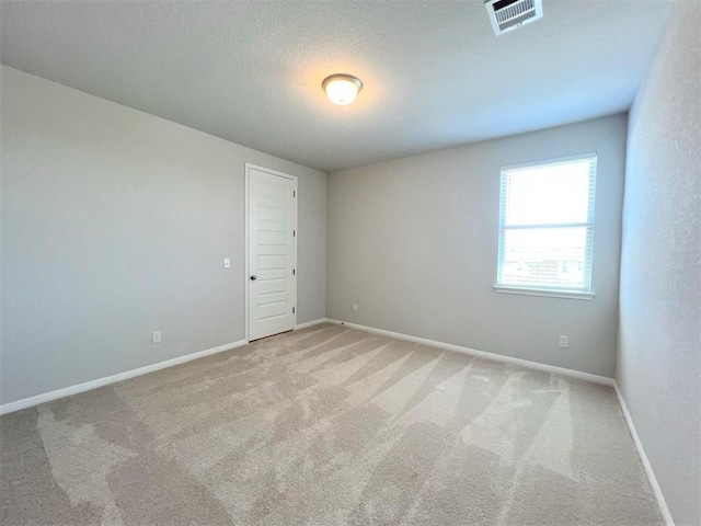 empty room with baseboards, visible vents, a textured ceiling, and carpet flooring