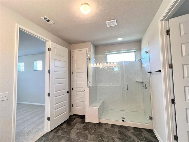 bathroom with baseboards, visible vents, a shower stall, and a textured ceiling