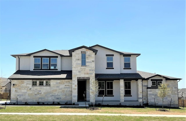 view of front facade featuring stone siding, fence, a front lawn, and stucco siding