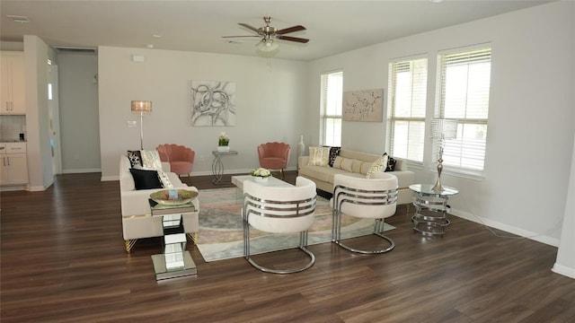 living room with a ceiling fan, baseboards, and dark wood-type flooring