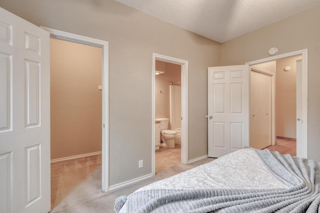 carpeted bedroom featuring baseboards, ensuite bath, a spacious closet, a textured ceiling, and a closet