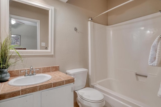 full bathroom featuring toilet, a textured wall, shower / bath combination, and vanity