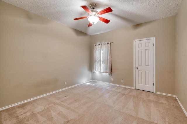 spare room featuring light colored carpet, ceiling fan, a textured ceiling, and baseboards