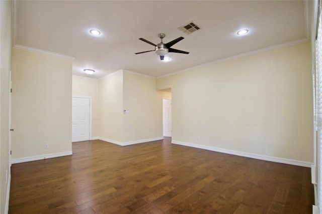 spare room featuring dark wood finished floors, visible vents, ornamental molding, a ceiling fan, and baseboards