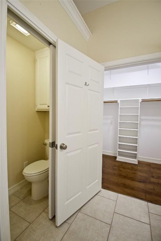 bathroom with toilet, baseboards, crown molding, and tile patterned floors