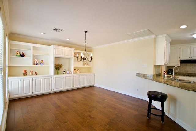 kitchen featuring crown molding, visible vents, dark wood-type flooring, white cabinetry, and a sink