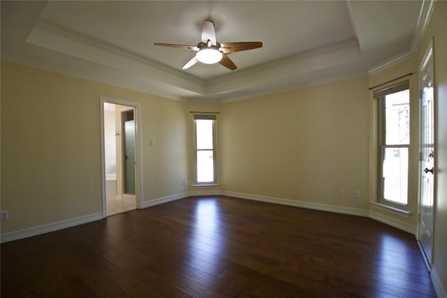 unfurnished room featuring a tray ceiling, dark wood-type flooring, and baseboards