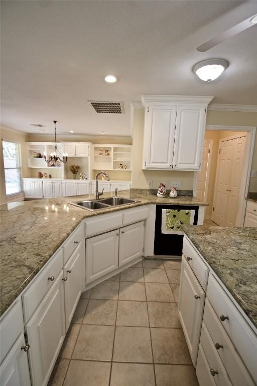 kitchen with white cabinets, a sink, visible vents, and crown molding