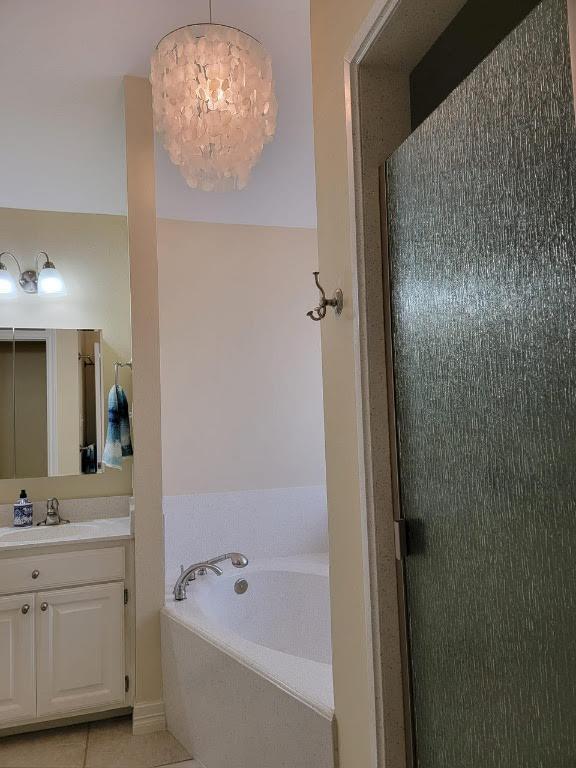 bathroom featuring a stall shower, vanity, a chandelier, tile patterned flooring, and a bath