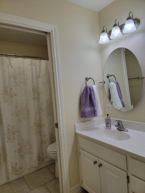 full bath with toilet, a shower with curtain, vanity, and tile patterned floors