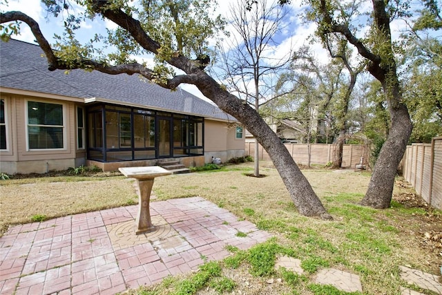 view of yard with a patio area, a fenced backyard, and a sunroom