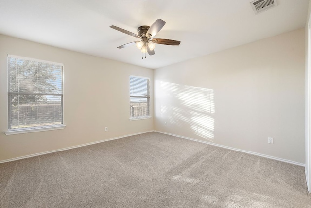 carpeted empty room featuring baseboards, visible vents, and a ceiling fan