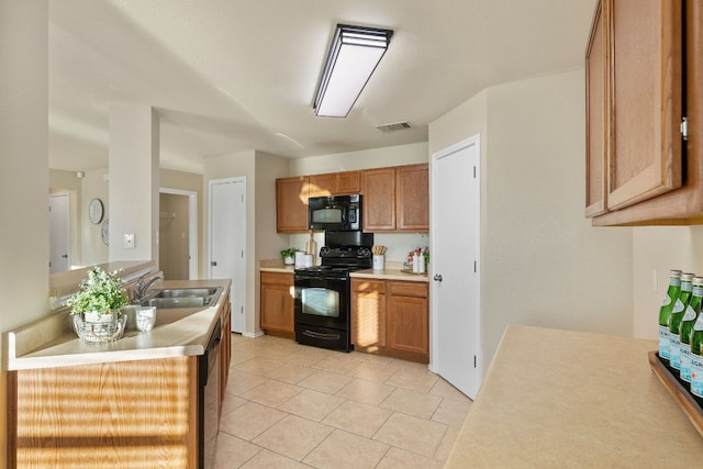 kitchen featuring light countertops, visible vents, brown cabinetry, a sink, and black appliances