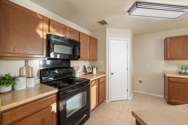 kitchen featuring visible vents, brown cabinets, light countertops, a textured ceiling, and black appliances