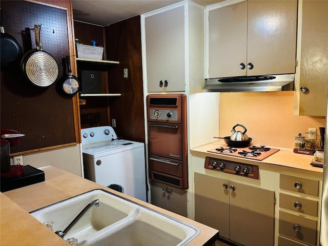 kitchen with wall oven, under cabinet range hood, a sink, light countertops, and washer / dryer