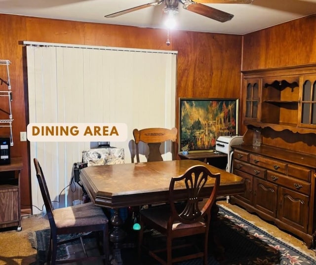 dining room featuring wood walls and a ceiling fan