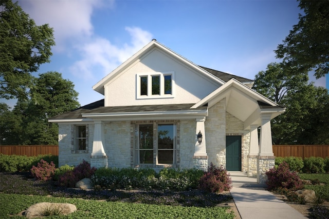 view of front of house featuring stone siding, fence, and stucco siding