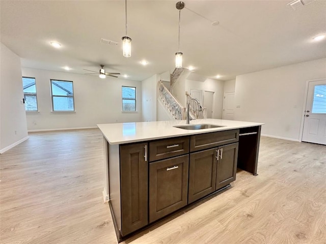 kitchen with a sink, light wood finished floors, open floor plan, baseboards, and recessed lighting