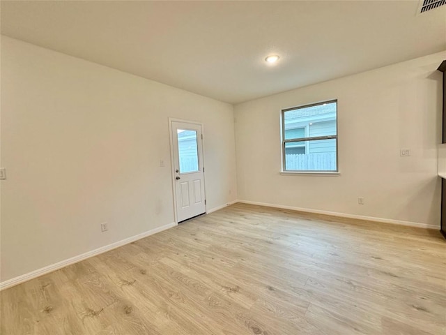 spare room with healthy amount of natural light, light wood-style flooring, and baseboards