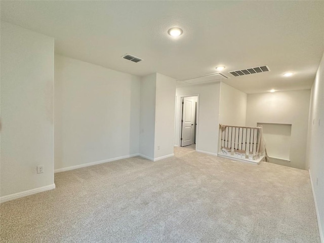 unfurnished room with attic access, carpet flooring, and baseboards