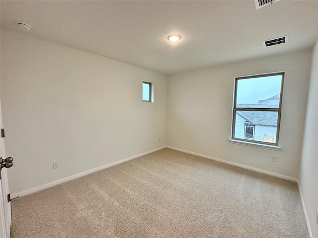 spare room featuring light colored carpet, baseboards, and a smoke detector