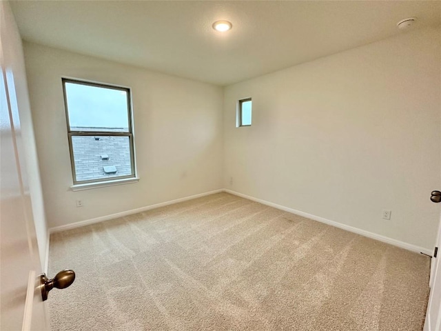 empty room featuring light carpet and baseboards