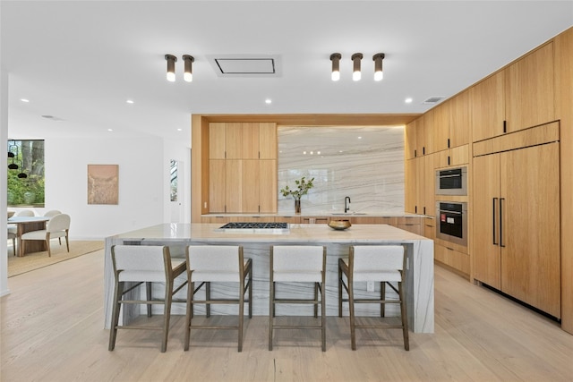 kitchen with a breakfast bar, stainless steel gas stovetop, paneled refrigerator, and modern cabinets