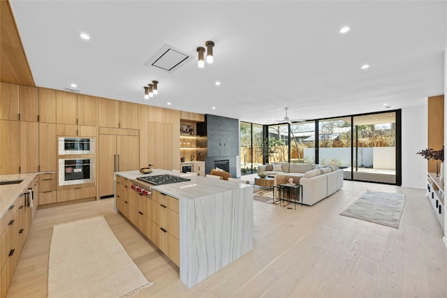 kitchen featuring floor to ceiling windows, stainless steel gas cooktop, a large fireplace, modern cabinets, and paneled fridge