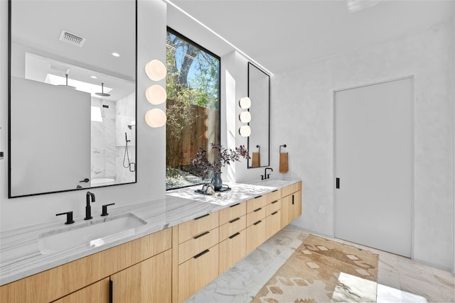 full bathroom with marble finish floor, double vanity, visible vents, a sink, and walk in shower