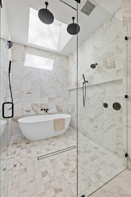 full bathroom with a skylight, tile walls, a soaking tub, visible vents, and a stall shower