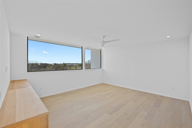 spare room with light wood finished floors, baseboards, visible vents, and a ceiling fan