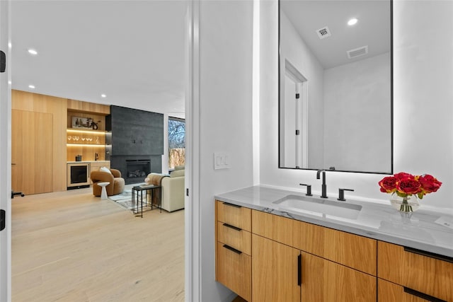 bathroom featuring a fireplace, wood finished floors, visible vents, and recessed lighting