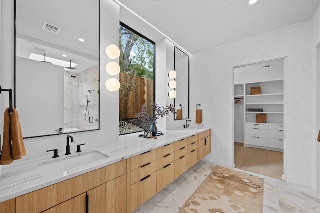 full bath with marble finish floor, a sink, a shower stall, and double vanity