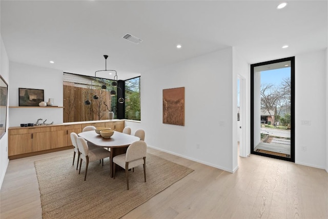 dining space featuring light wood-type flooring, visible vents, a wall of windows, and recessed lighting