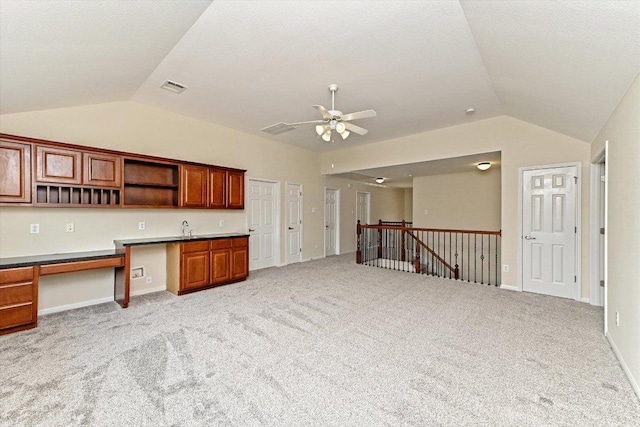 kitchen with vaulted ceiling, open shelves, built in study area, and visible vents