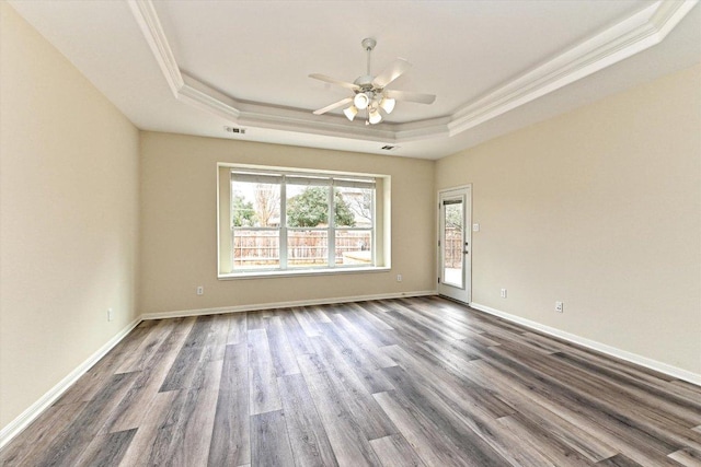 unfurnished room with dark wood-style floors, a tray ceiling, visible vents, and baseboards