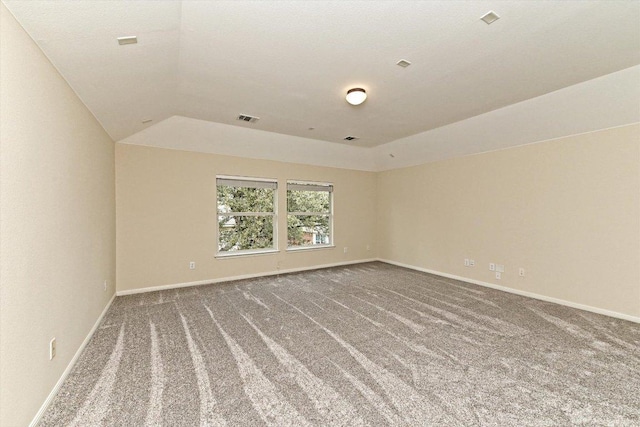 carpeted empty room with visible vents, vaulted ceiling, and baseboards