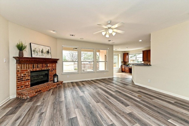 living area featuring dark wood-type flooring, visible vents, a fireplace, and baseboards