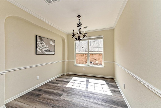 unfurnished dining area featuring a notable chandelier, ornamental molding, wood finished floors, and baseboards