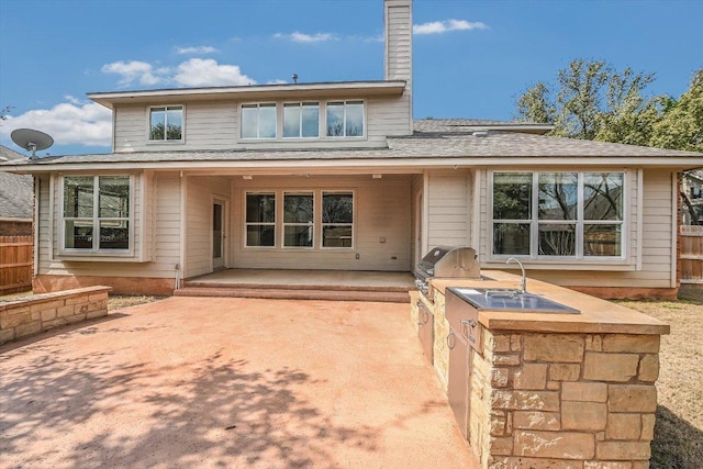 back of property with a patio area, a chimney, fence, and area for grilling