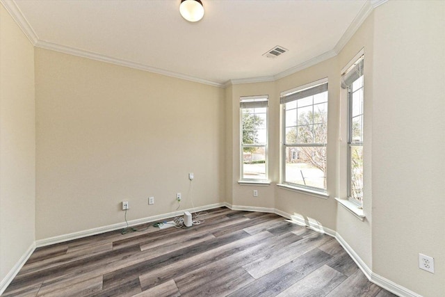 spare room featuring baseboards, visible vents, crown molding, and wood finished floors