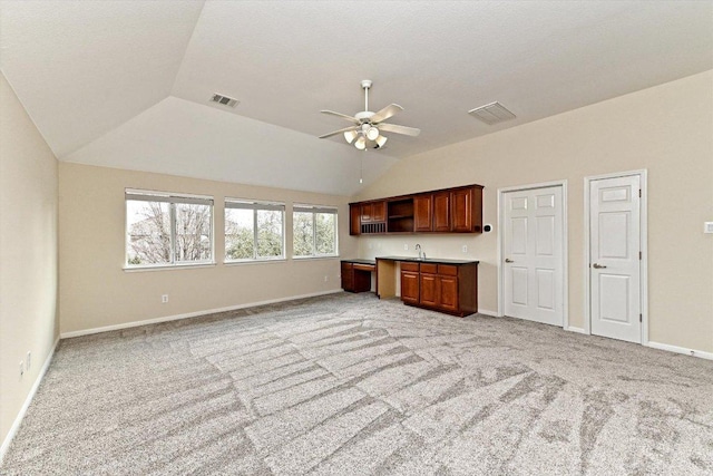 unfurnished living room with light carpet, baseboards, and vaulted ceiling