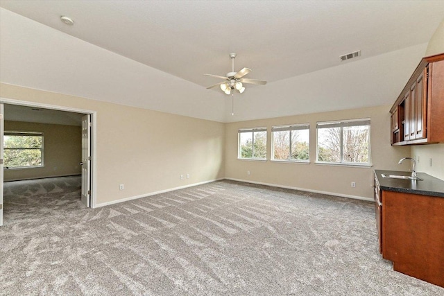 unfurnished living room with plenty of natural light, carpet, a sink, and baseboards