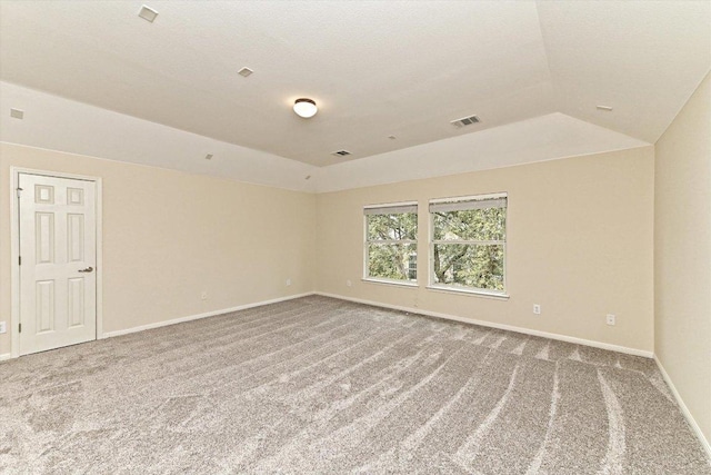 empty room featuring vaulted ceiling, carpet flooring, visible vents, and baseboards